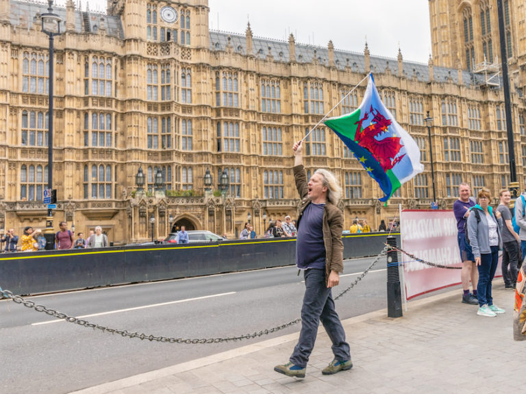 Anti-Brexit protester carries Wales and European Union flags outside Parliament in Westminster